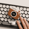 Retro Bluetooth Earbuds with LED Display Retro-style Bluetooth earbuds with LED display on a keyboard.
